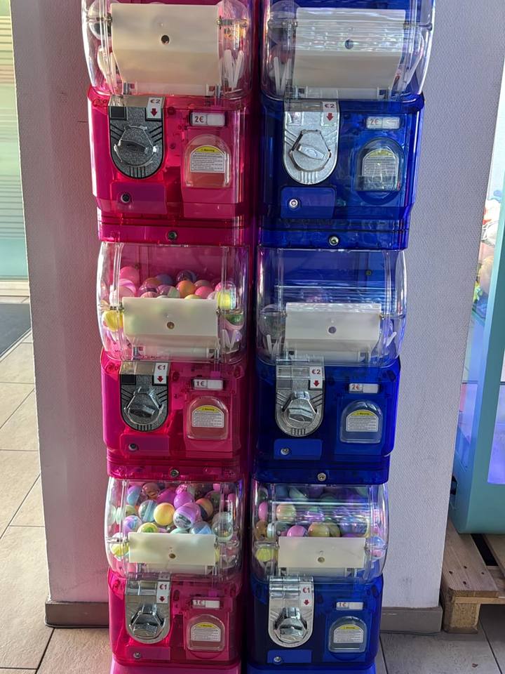 Sechs gestapelte Kapselautomaten in Pink und Blau mit bunten Kugeln