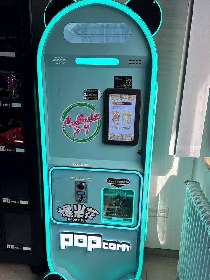 Popcornautomat mit Leuchtrand und Pandaohren, daneben das MaxiBude-Logo